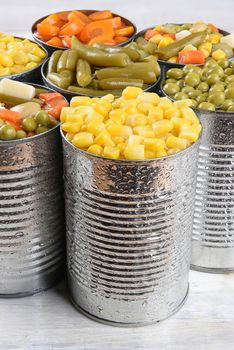 Closeup of a group of canned vegetables. Seven cans of mixed veggies, corn, peas, carrots and green beans.