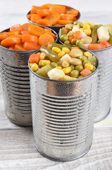 Closeup of a group of cans of mixed vegetables and carrots.