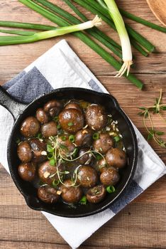 Top view of a cast iron skillet with sauteed mushrooms.