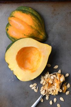 High angle view of an Acorn Squash cut in half on a metal baking sheet with a spoon and seeds scooped out.