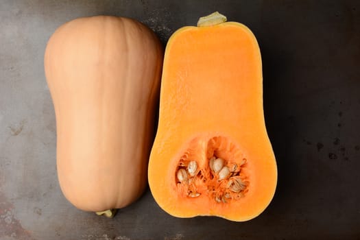 Butternut Squash on a metal cooking sheet. The fruit is cut in half showing both the inside and outside. Horizontal format. 