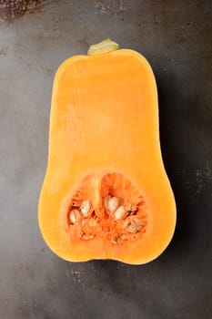 Butternut Squash on a metal cooking sheet. The vegetable is cut in half showing the inside. Vertical format.