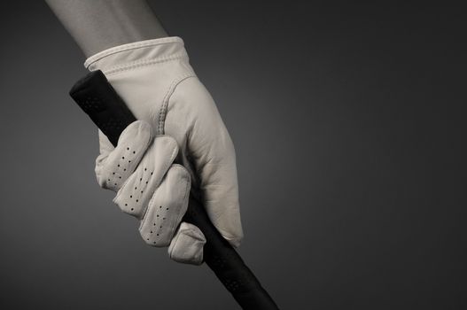 Closeup of a golfers hand on the handle of a golf club. Horizontal format on a light to dark background. Slight sepia toning for an old fashioned look.