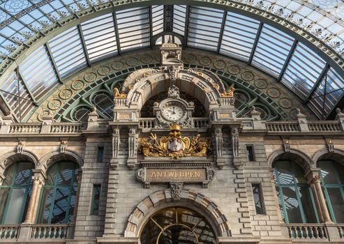 Antwerp, Belgium - September 24, 2018: Clock and coat of arms of town on Train hall facade of Antwerpen Central Station. Glass roof, facade.
