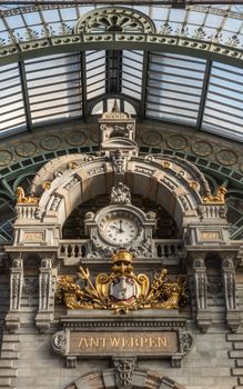 Antwerp, Belgium - September 24, 2018: Closeup of Clock and coat of arms of town on Train hall facade of Antwerpen Central Station. Glass roof.