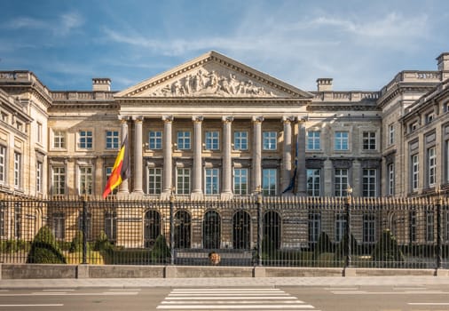 Brussels, Belgium - September 26, 2018: Facade of Belgian Parliament in romanesque style with pillars and fresco triangle, black-gold fence and Belgian and European flag. Front is Wetstraat.