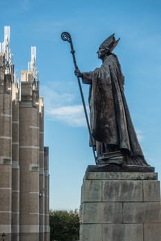 Brussels, Belgium - September 26, 2018: Bronze statue of Catholic Cardinal Mercier on stone pedestal against blue sky looking at office building.