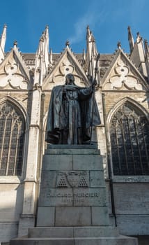 Brussels, Belgium - September 26, 2018: Bronze statue of Catholic Cardinal Mercier on stone pedestal with nave of Cathedral in back. Blue sky.