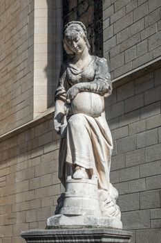 Brussels, Belgium - September 26, 2018: The white stone milk maid statue on side of Saint Nicolas church downtown a stone throw away from Grand Place. Gray stone church wall in back.