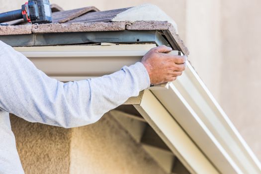 Worker Attaching Aluminum Rain Gutter to Fascia of House.