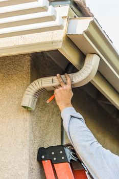 Worker Attaching Aluminum Rain Gutter and Down Spout to Fascia of House.