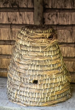 Bokrijk, Belgium - June 27, 2019: Closeup of classic large yellowish-brown straw beehive set under awning.