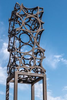 Amsterdam, the Netherlands - June 30, 2019: Closeup of tall rusted artwork, sculpture of metal circles welded together and set against blue sky with some white clouds.