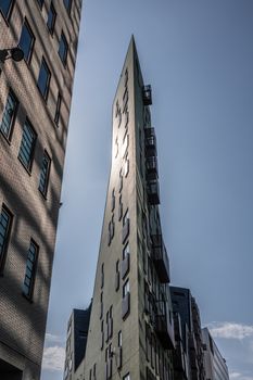 Amsterdam, the Netherlands - June 30, 2019: Trangular high rise office building and hotel ending in ultra sharp corner set against blue sky and hit by morning sun.