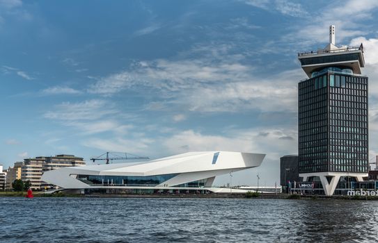 Amsterdam, the Netherlands - June 30, 2019: White Eye Film Museum and A’Dam lookout tower under blue sky with some white clouds. IJ water in front.