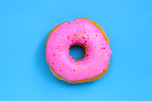 Pink donut on blue background. Top view