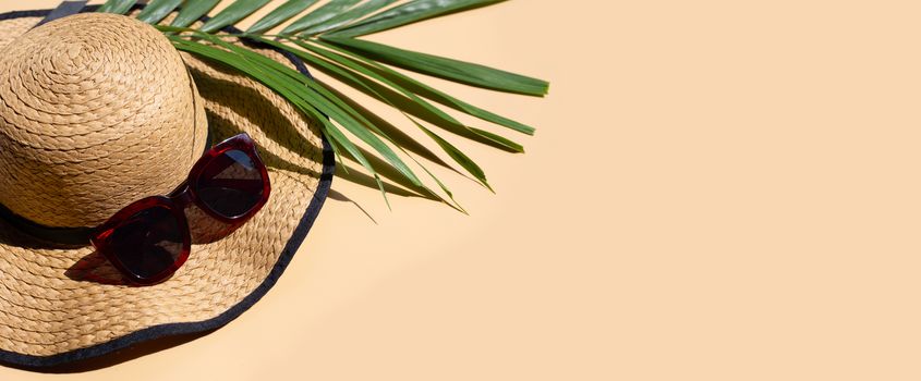 Summer hat with sunglasses and tropical palm leaves on brown background. Enjoy holiday concept. Copy space
