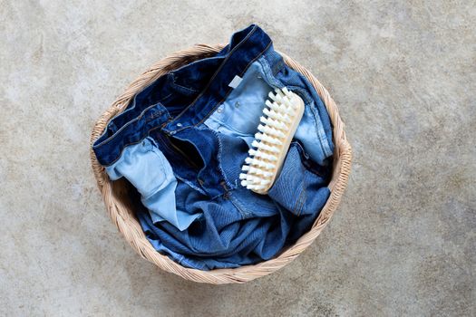 Jeans in laundry basket on cement floor background. Top view