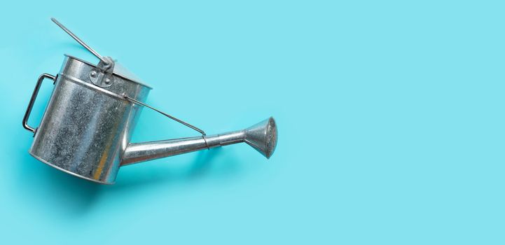 Watering can on blue background. Copy space