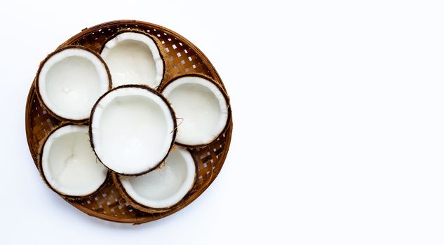 Half coconuts on wooden bamboo threshing basket on white background. Copy space
