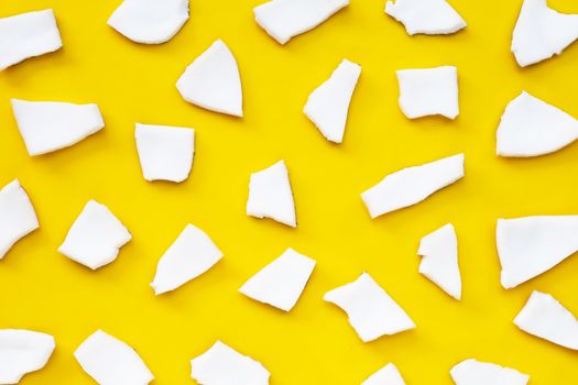 Coconut cut pieces on yellow background. Top view