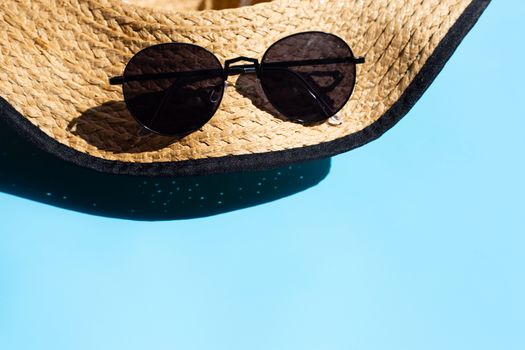 Hat and sunglasses on blue background. Enjoy summer holiday concept. Copy space