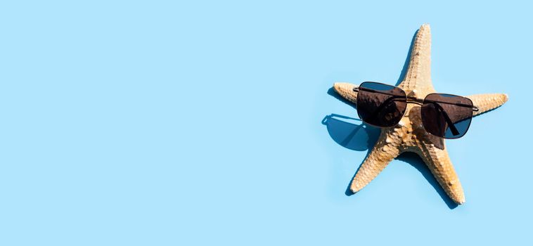 Starfish with sunglasses on blue background. Enjoy summer holiday concept. Copy space