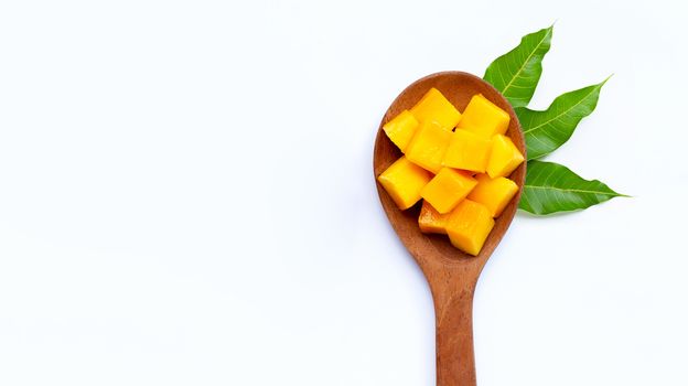 Sliced ripe mango cubes on wooden spoon on white background. Copy space