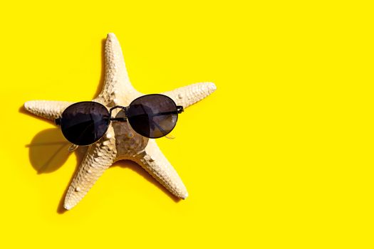 Starfish with sunglasses on yellow background. Enjoy summer holiday concept. Copy space