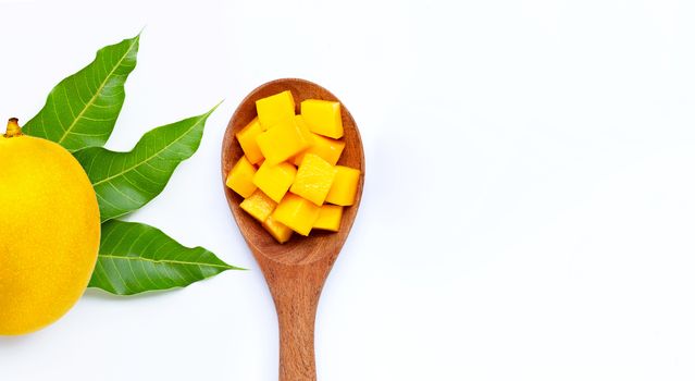 Sliced ripe mango cubes on wooden spoon on white background. Copy space