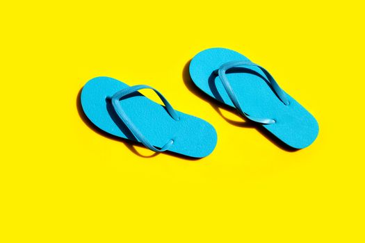 Blue flip flops on yellow background. Top view