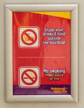Amsterdam, the Netherlands - June 30, 2019: Funny sign saying No Smoking Unless You Are On fire, sponsored by City Sightseeing companies. Reds and yellows.