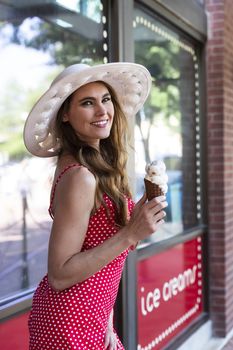 A beautiful Brunette model posing outdoors while eating ice cream in an urban environment