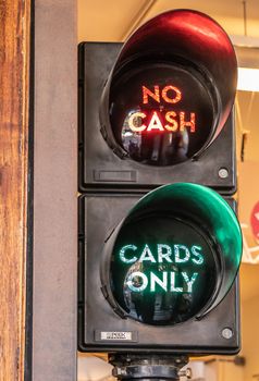 Amsterdam, the Netherlands - July 1, 2019: Closeup of traffic light displaying two options at check-out in retail store: no cash om red, cards only in green.