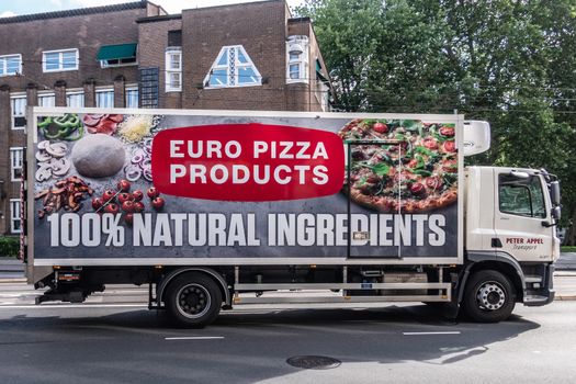 Amsterdam, the Netherlands - July 1, 2019: Euro Pizza producer and merchant deliver truck. Side plastered by huge photos of Pizza and ingredients. Street scene with green foliage.