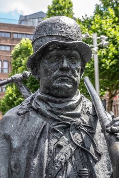 Amsterdam, the Netherlands - July 1, 2019: De Nachtwacht compostion of statues on Rembrandtplein. Closeup of bust of one of several gun carrying figures against green foliage.
