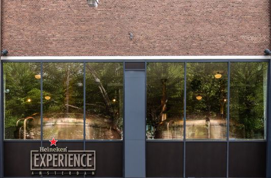 Amsterdam, the Netherlands - July 1, 2019: Heineken Experience exhibition and tour in historic Heineken brewery along Stadhouderskade shows large window with brew kettles behind.