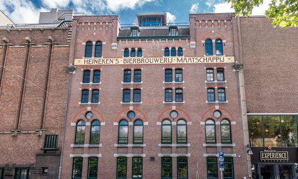 Amsterdam, the Netherlands - July 1, 2019: Red brick facade of historic Heineken brewery along Stadhouderskade has name spelled out in brown on beige.