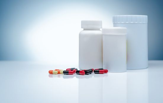 Antibiotic capsule pills and blank label plastic drug bottle on gradient background. Pharmaceutical industry. Antibiotic drug resistance. Antimicrobial capsule pills. Pharmaceutical manufacturing.