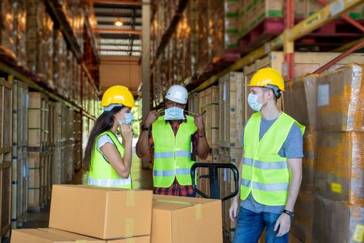 Warehouse workers wearing protective mask to Protect Against Covid-19 with clipboard during work in a warehouse.