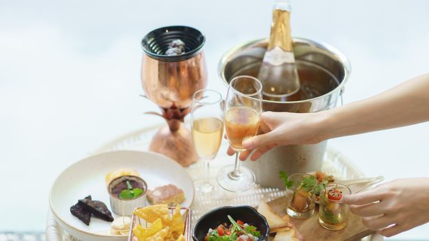 Woman hand holds glass of wine with different snacks and appetizers food at a cocktail party.