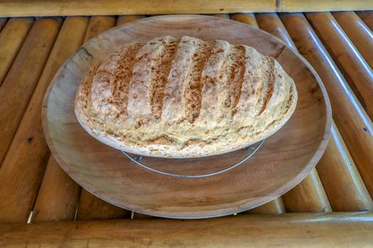 Fresh homemade bread made of wheat and rye flour. Sliced bread in a wicker basket. Bowl with salt. Delicious homemade pastries in a wicker basket. Healthy food on bamboo background.