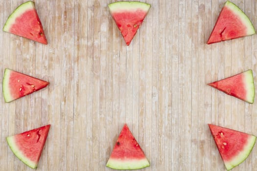 Triangular slices of watermelon that form geometric games for copy space on a light wooden background