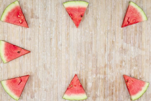 Triangular slices of watermelon that form geometric games for copy space on a light wooden background