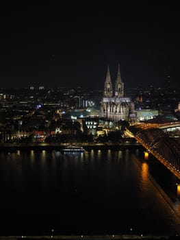 Night aerial view Koelner Dom Sankt Petrus (meaning St Peter Cathedral) gothic church and Hohenzollernbruecke (meaning Hohenzollern Bridge) crossing the river Rhein in Koeln, Germany