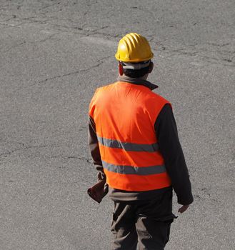 unrecognisable road construction worker with orange safety wear jacket and hard hat helmet