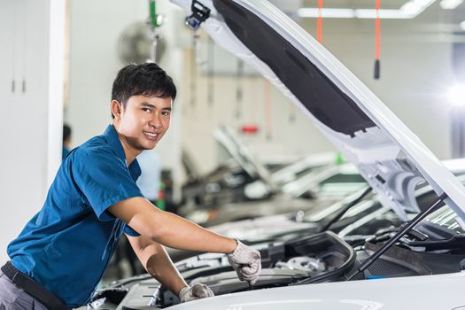 Asian mechanic Checking and repairing the car in maintainance service center which is a part of showroom, technician or engineer professional work for customer, car repair concept