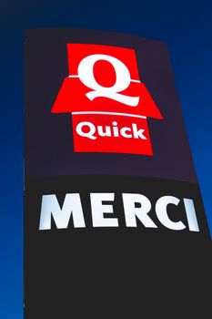 Olonne sur Mer, France - December 03, 2016 : Signs of the restaurant chain specialized in burgers "Quick" by night. The sign, located at the exit of the parking lot, bears the mention Thank you "Merci" in french
