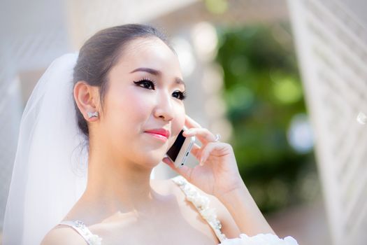 Happy bride talking on cell phone in wedding dress