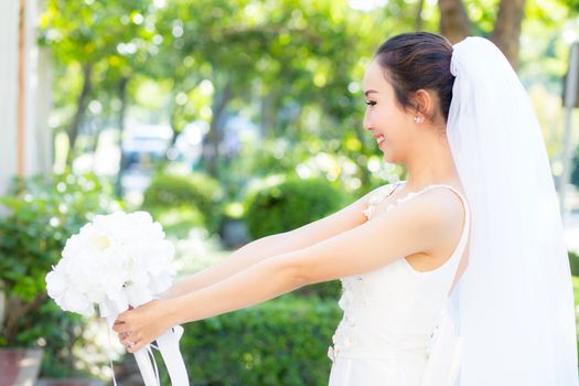 beautiful young woman on wedding day in white dress in the garden. Female portrait in the park.